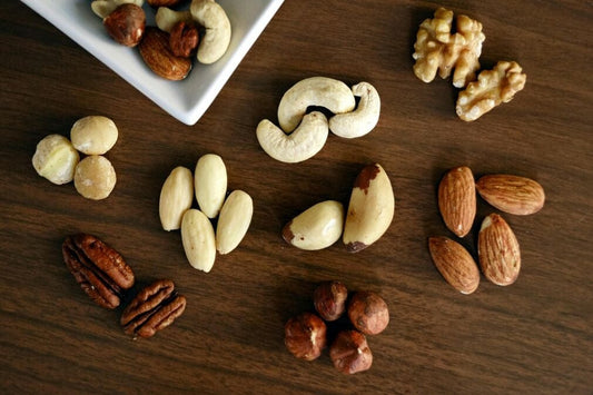 A selection of tree nuts in a flat lay, on a dark wooden surface, to illustrate common allergy nuts